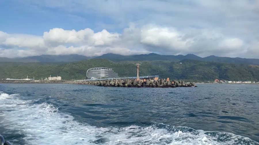 真正出海之後，再回頭看岸上。防波堤、燈塔、山，全都慢慢往後退。