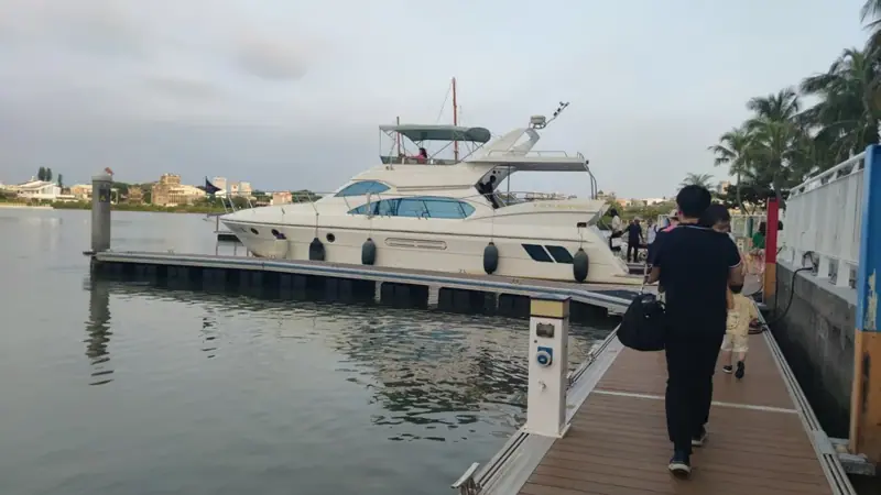 沿著碼頭步道往前走，白色遊艇停在左前方，準備登船。