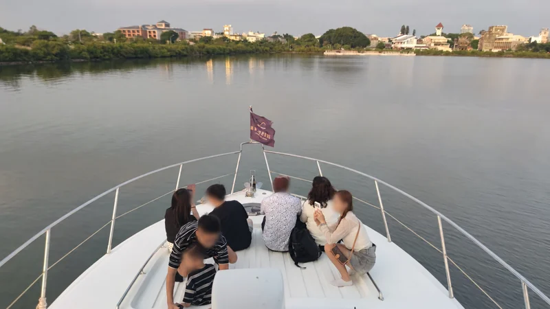 遊艇船首與欄杆在前景，隔著水面回望安平岸邊建築