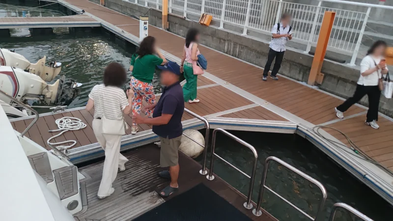 從遊艇往下看船尾登岸處，遊客走在浮動碼頭上，人物臉部已模糊處理。