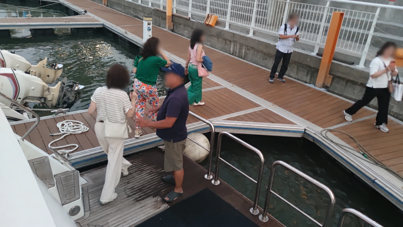 從遊艇往下看船尾登岸處，遊客走在浮動碼頭上，人物臉部已模糊處理。
